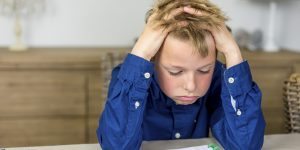 boy struggling with his homework, holding his hands in his hair